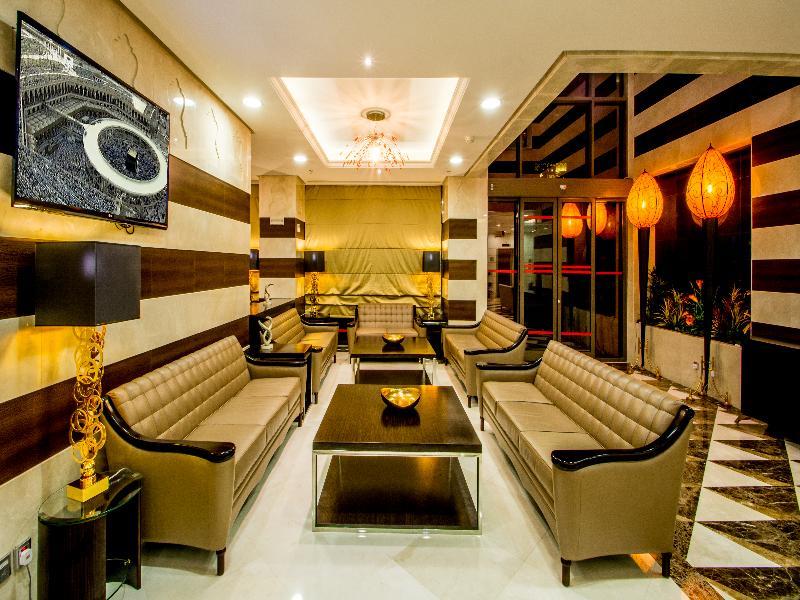 Al Aqeeq Madinah Hotel Medina Exterior foto The photo shows a modern and stylish living area or lounge. It features several beige leather sofas arranged around a central black coffee table. The walls are decorated with a mix of light colors and dark wooden accents. There is a large flat-screen